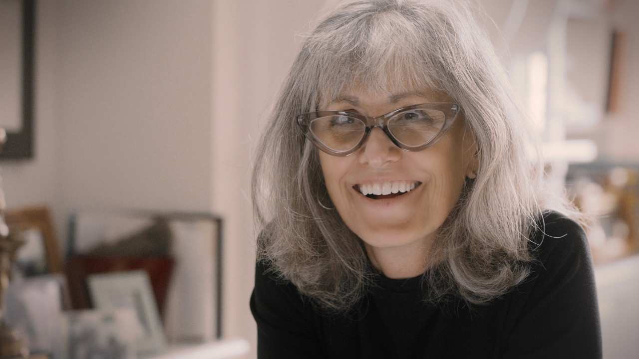 a woman with glasses smiling at the camera